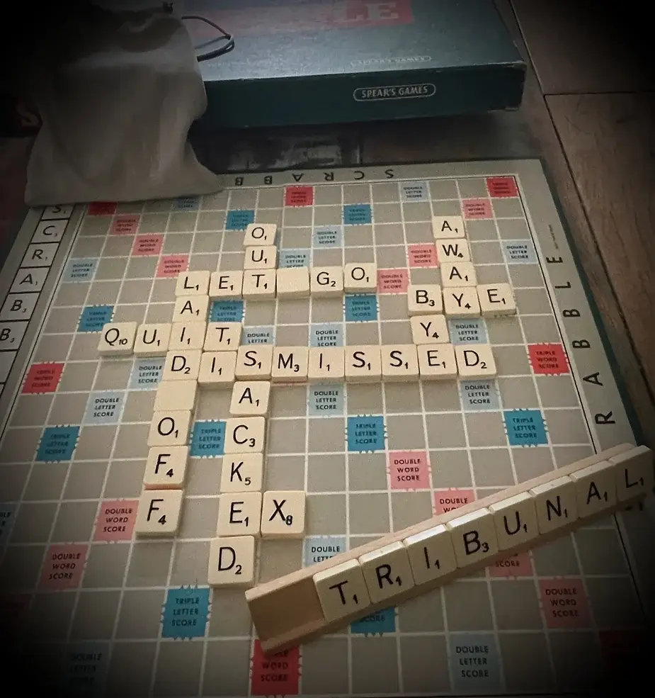 A scrabble board with lots of words relating to dismissal on it to illustrate the power of words.