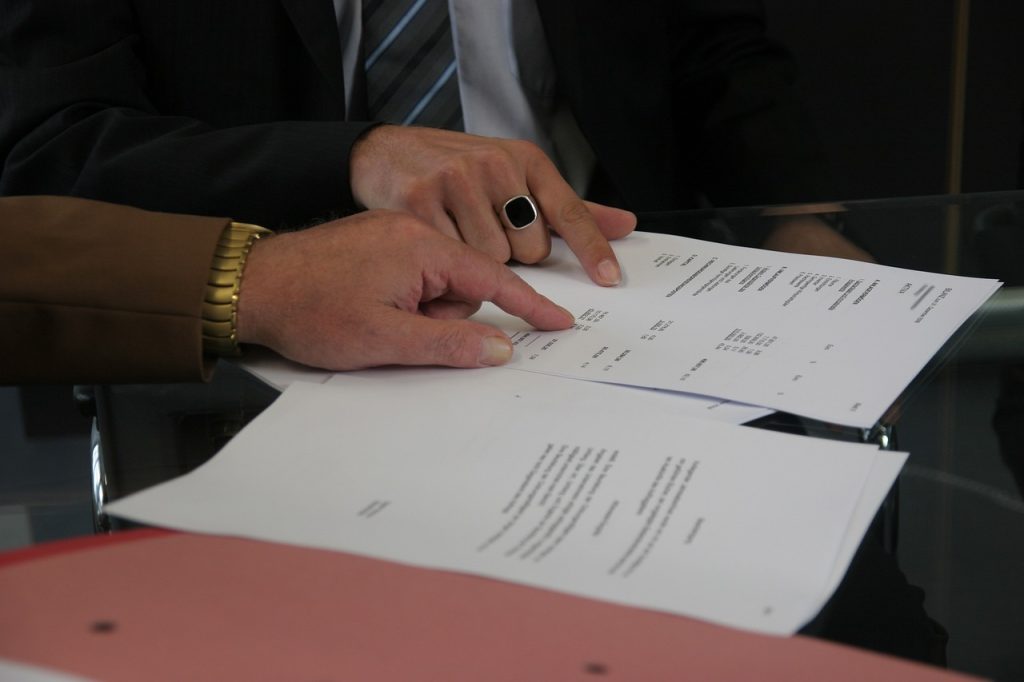 Zoomed in photo of two people's hands pointing at a financial report.