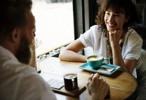 Two people in an informal business meeting talking and drinking coffee