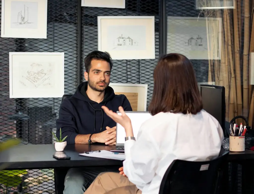 Two people sat across a table informally, drinking coffee and talking.