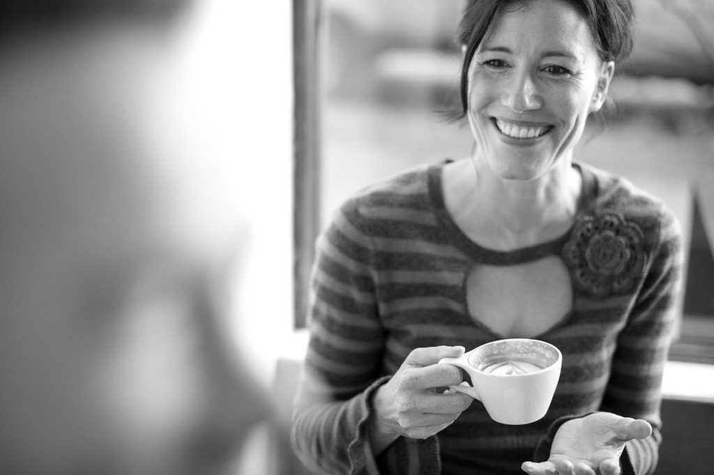 A woman in deep conversation holding a cup of coffee